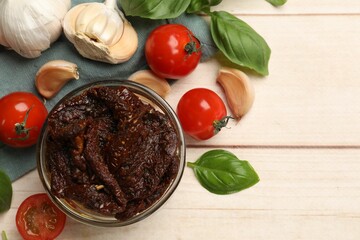 Delicious sun dried tomatoes, fresh vegetables, basil and garlic on white wooden table, flat lay
