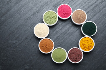 Different superfood powders on black table, flat lay. Space for text
