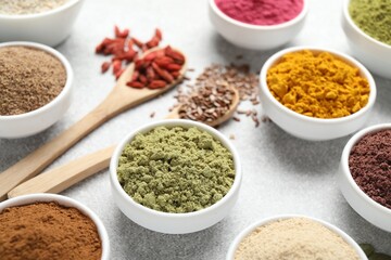 Different superfood powders on light grey table, closeup