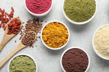 Different superfood powders on light grey table, flat lay