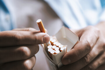 Man taking cigarette out of pack, closeup. Smoking
