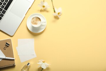 Flat lay composition with stationery, coffee and flowers on beige background. Space for text