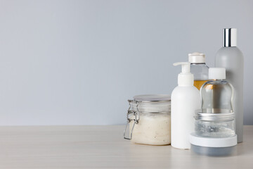Different bath accessories on light wooden table against grey background, closeup. Space for text
