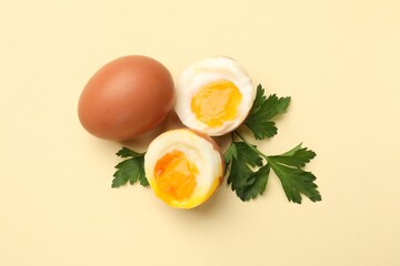 Soft boiled eggs and parsley on beige background, flat lay