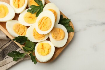 Boiled eggs and parsley on white marble table, top view. Space for text