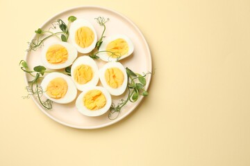 Boiled eggs and microgreens on beige background, top view. Space for text