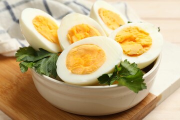 Boiled eggs and parsley in bowl on table, closeup