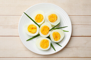 Boiled eggs and green onions on wooden table, top view