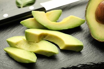 Tasty ripe green avocado and knife on table, closeup
