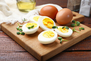 Halves of hard boiled eggs with microgreens on wooden table, closeup