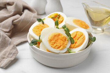 Halves of hard boiled eggs with microgreens on white table, closeup