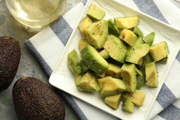 Tasty cut avocados with dressing on grey textured table, flat lay