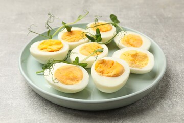 Hard boiled eggs with microgreens on grey table, closeup