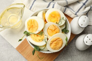 Hard boiled eggs with microgreens on grey table, flat lay