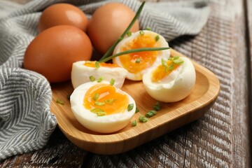 Soft boiled eggs with green onions on wooden table, closeup
