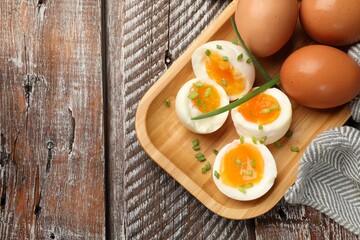 Soft boiled eggs with green onions on wooden table, top view. Space for text
