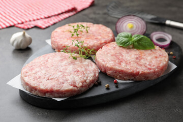 Fresh raw patties for burger and spices on grey table, closeup