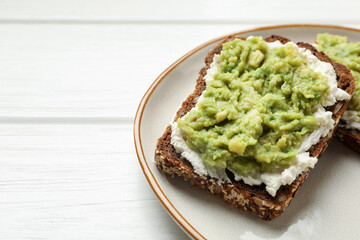 Delicious sandwiches with avocado and cream cheese on white wooden table, closeup. Space for text