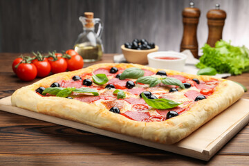 Tasty homemade pizza and ingredients on wooden table, closeup