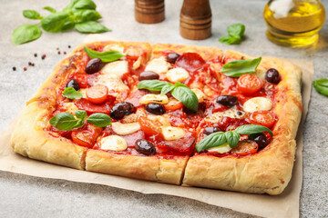 Tasty square homemade pizza and spices on grey background, closeup