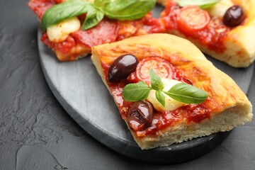 Pieces of tasty homemade pizza on black table, closeup