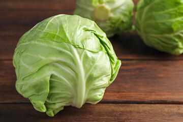 Fototapeta premium Fresh whole cabbages on wooden table, closeup. Space for text