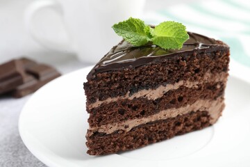 Piece of delicious chocolate cake with mint on table, closeup