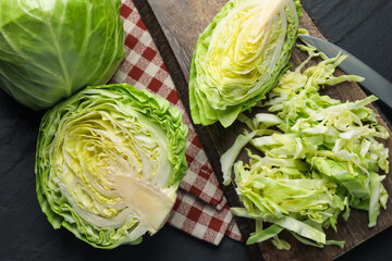 Fresh green cabbages and knife on black table, flat lay