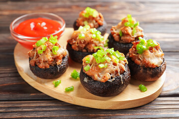 Delicious stuffed mushrooms and sauce on wooden table, closeup