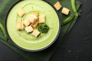 Tasty pea cream soup with croutons and broccoli served on black table, flat lay