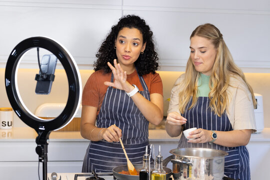 Cooking diverse female friends preparing sauce and seasoning in modern kitchen with ring light