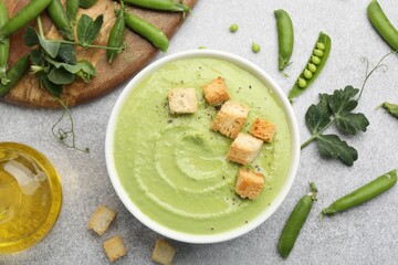Tasty pea cream soup with croutons served on grey table, flat lay