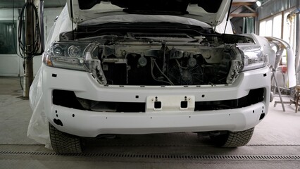 White suv undergoing bumper repair in auto body shop