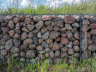 Retaining wall constructed of field stones and wire mesh.