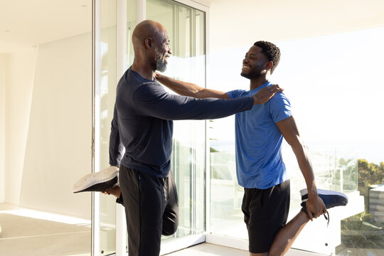 Stretching African American father and son balancing on balcony, holding foot with running shoes