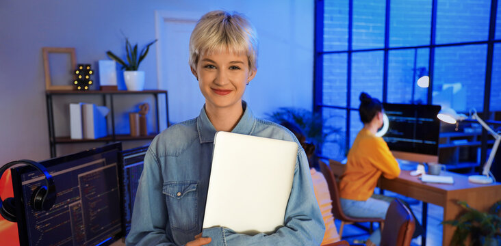 Female programmer with laptop in office at night