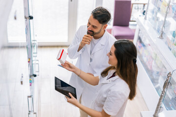 Pharmacists Selecting Medicine from Shelf Using Tablet in Pharmacy