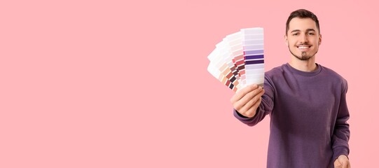 Young man with color palettes on pink background with space for text