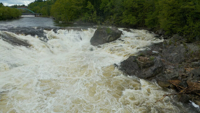 Aerial View of Flowing River with Foam Patterns and Forest Shoreline in Maine