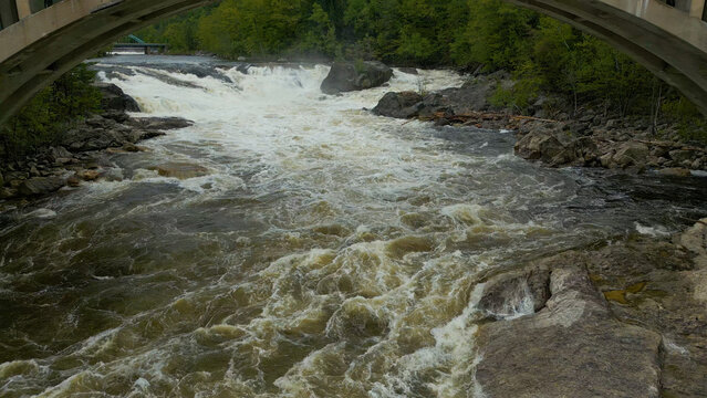 Aerial View of Flowing River with Foam Patterns and Forest Shoreline in Maine