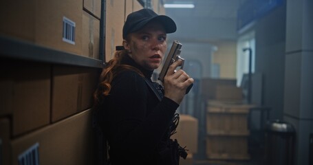 Female Secret Agent in Black Tactical Gear and Cap Hiding in Warehouse, Holding a Weapon, Talking...