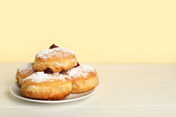 Plate with tasty donuts for Hanukkah celebration on light wooden table
