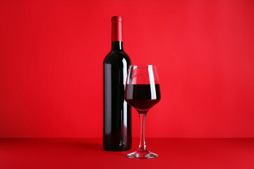 Bottle and glass of red wine on color background