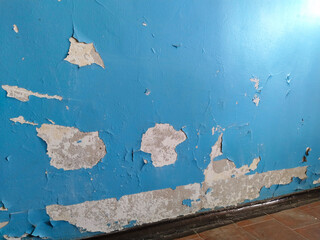 Old home. residential building. Cracked blue paint on wall. Dirty floor. Cleaning. Peeling painted background. House repair. Housing service. Plaster. Damaged. entrance walls are in terrible condition