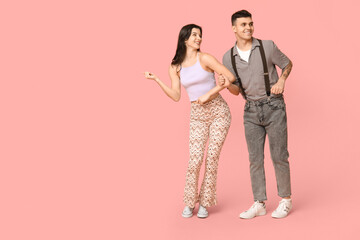 Happy young couple dancing on pink background