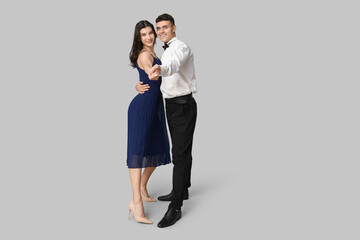 Happy young couple dancing on grey background