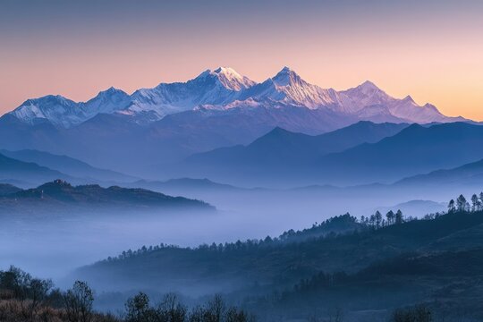 Serene mountain range at dawn, with snow-capped peaks and layers of misty valleys creating a tranquil landscape.