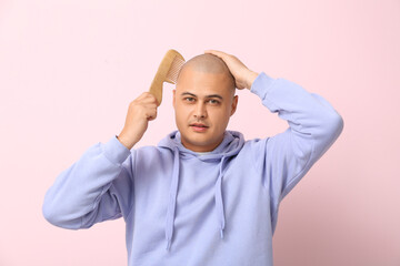Bald young man with comb on pink background