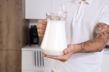 Young man with jug of milk in kitchen, closeup