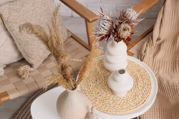 Vases with dried flowers and pampas grass on tables in living room, closeup